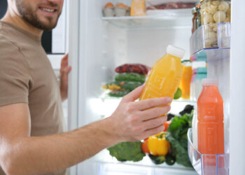 Mann holt Saft aus dem Kühlschrank