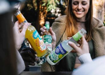 Junge Leute stoßen mit Limos in Longneckflaschen an