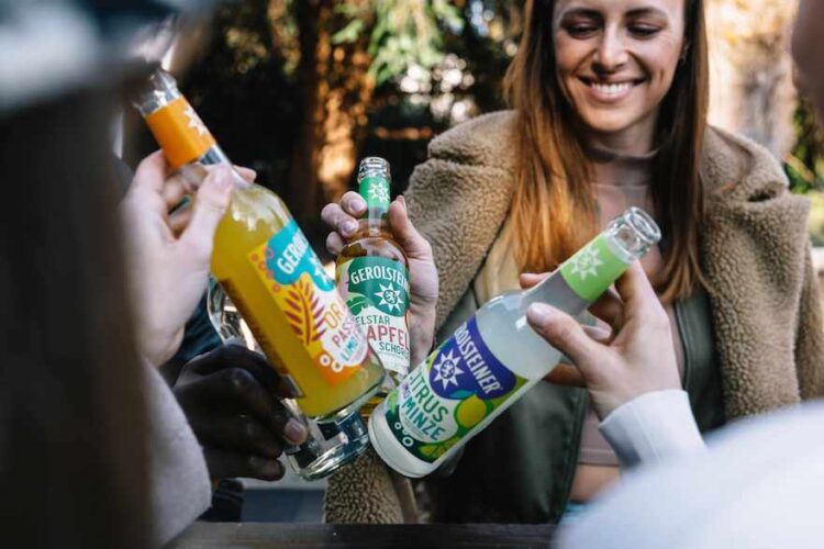 Junge Leute stoßen mit Limos in Longneckflaschen an