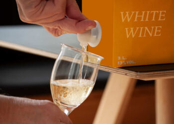 Hand füllt Wein aus Bag-in-Box in ein Glas