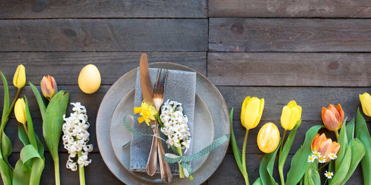 Teller und Bestecke auf einem mit Frühlingsblumen geschmückten Tisch