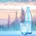 Wasserflasche und Glas vor winterlicher Gebirgslandschaft