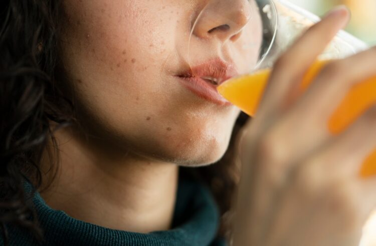 Junge Frau, die Orangensaft trinkt