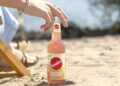 Frau am Strand mit einer Flasche Sinalco Leichte Limo in der Longneckflasche