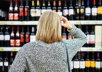Frau vor einem Weinregal im Supermarkt