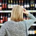 Frau vor einem Weinregal im Supermarkt