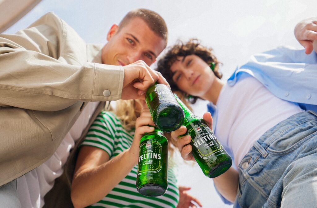 Foto von drei jungen Erwachsenen mit einer Flasche Veltins Helles lager