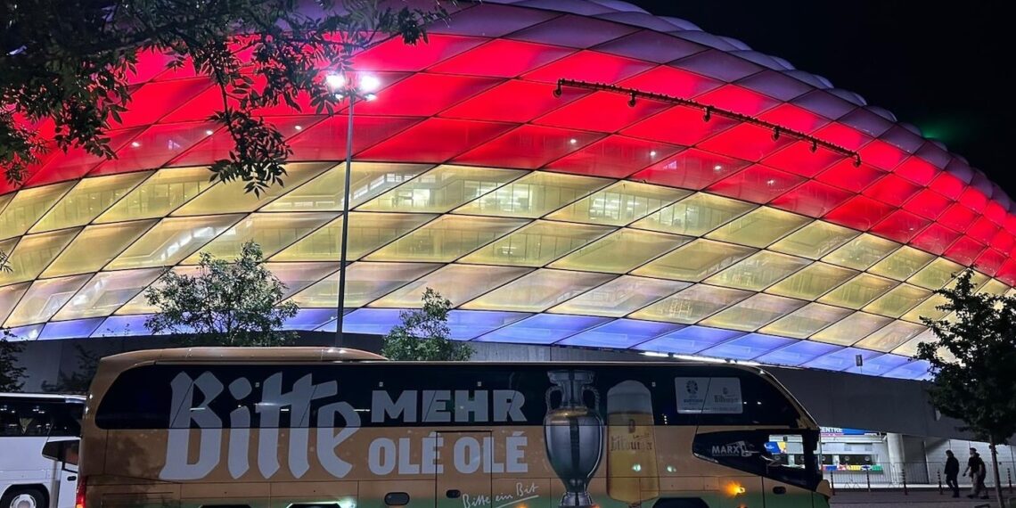 Bus mit Bitburger-Schriftzug vor beleuchtetem EM-Stadion