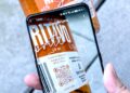 Smartphone, das einen QR-Code auf einer Flasche scannt