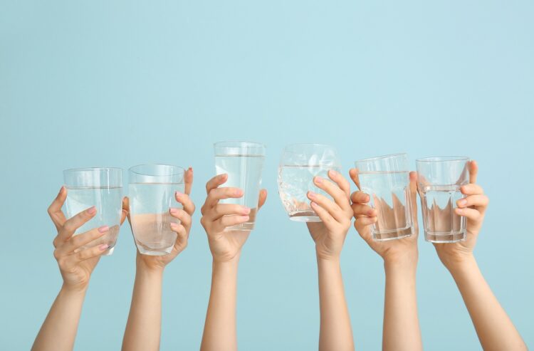 Frauenhände halten Wassergläser hoch