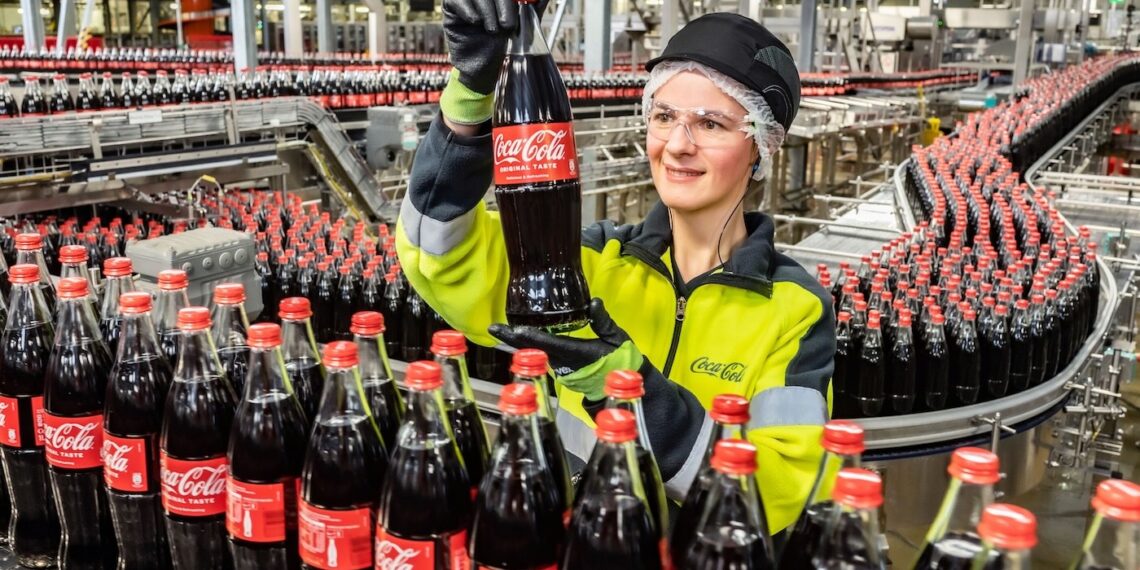 Mitarbeiterin an einer Glas-Linie von Coca-Cola