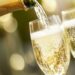 Sekt wird aus Flasche in zwei Gläser geschenkt