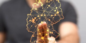 Durchsichtige Deutschlandkarte mit vielen Ortspunkten, die durch Linien verbunden sind, im Hintergrund unscharf ein Mann, der seine Hand auf die Karte legt