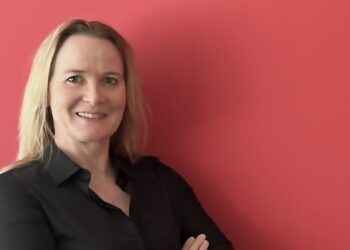 Porträt von Claudia Bensch, schwarz gekleidet vor rotem Hintergrund