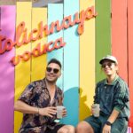 Lars Steinhöfel und Mirielle Boho vor einer Wand im Regenbogendesign mit dem Schriftzug "Stolichnaya Vodka"