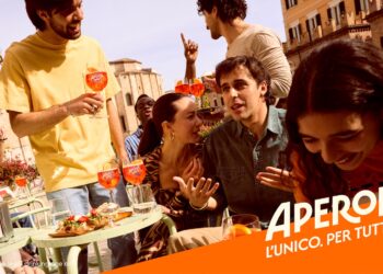 Aperol-Werbemotiv: Lebhafte Szene auf einer italienischen Piazza, junge Leute trinken Aperol Spritz