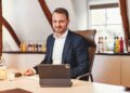 Oliber Schwegmann mit einem Laptop am Schreibtisch, im Hintergrund Flaschen des Berentzen-Sortiments