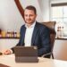 Oliber Schwegmann mit einem Laptop am Schreibtisch, im Hintergrund Flaschen des Berentzen-Sortiments
