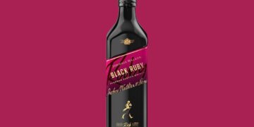 Eine Flasche Johnnie Walker Black Ruby vor weinrotem Hintergrund
