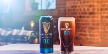 Eine Dose und ein Glas Guinness 0.0 vor einer Backsteinwand