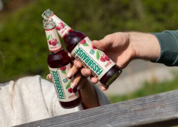 Eine Frau und ein Mann stoßen mit Krombacher's Fassbrause Kirsche an, zu sehen sind nur die Arme.