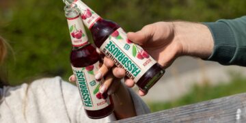 Eine Frau und ein Mann stoßen mit Krombacher's Fassbrause Kirsche an, zu sehen sind nur die Arme.