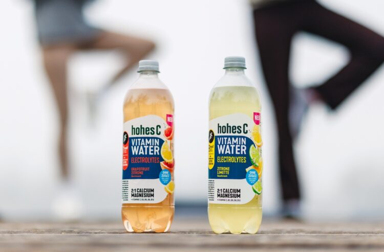 Die beiden neuen Sorten Hohes C Vitamin-Water, im Hintergrund Menschen beim Yoga
