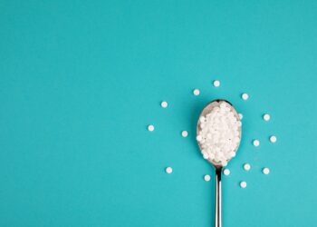 Süßstofftabletten auf einem Löffel vor blauem Hintergrund